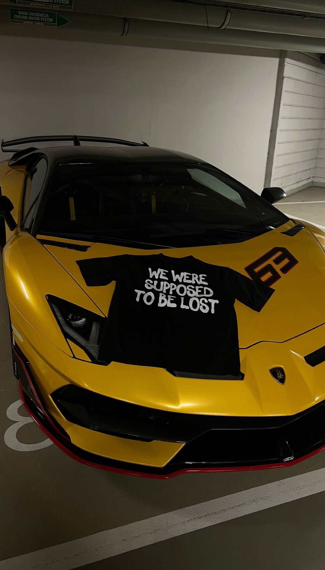 LOSTGEN tee laid on a yellow supercar